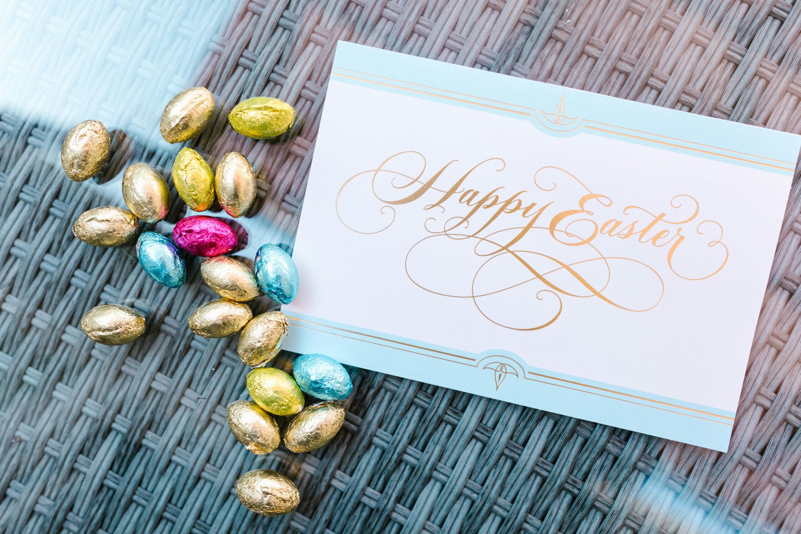Beautiful Easter card with colorful chocolate eggs on a woven surface.